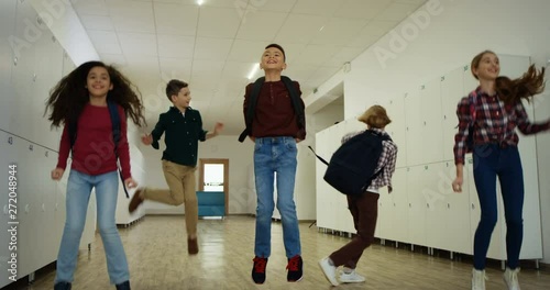 Cheerful happy Caucasian kids running the school coridor, jumping and having fun after teir lessons or during a break. photo