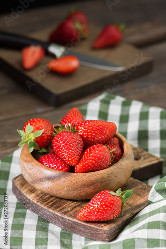 Strawberry in wooden bowl on wooden background. Rustic style