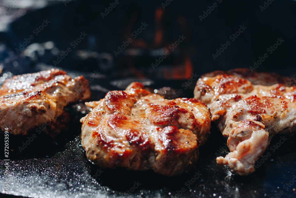 Some patties of ground meat with a flame in the front on cooking grate.