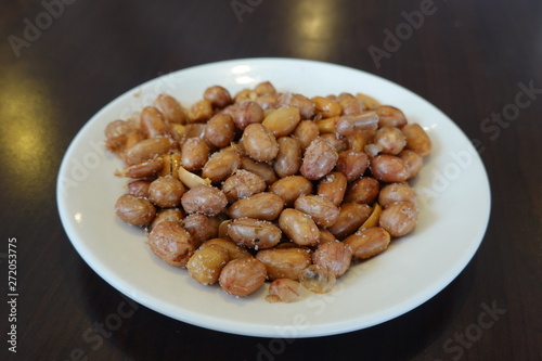 A plate of salted peanuts is on the table. A common side dish in Taiwanese restaurants. Food concept. Peanuts are rich in essential nutrients.