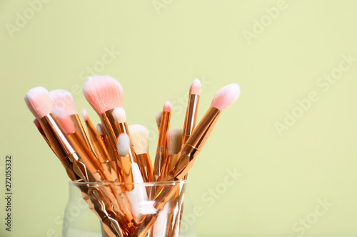 Jar with makeup brushes against color background. Space for text