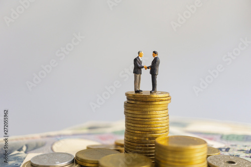 Leader businessman suits handshake stand among on stack of coin and money. Financial banner concept. photo