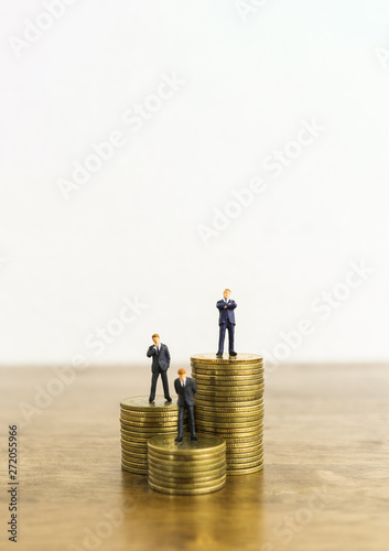 business growth and investment level up concept. a little figure miniature businessman stand on stacks of coins.