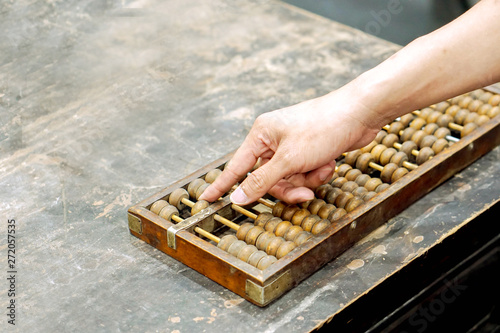 Hand of person playing and demonstration used of ancient Chinese abacus on old black wooden table. photo