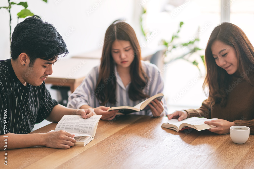 Group of young people sitting and enjoyed reading books together on wooden table Group of young people sitting and enjoyed reading books together on wooden table