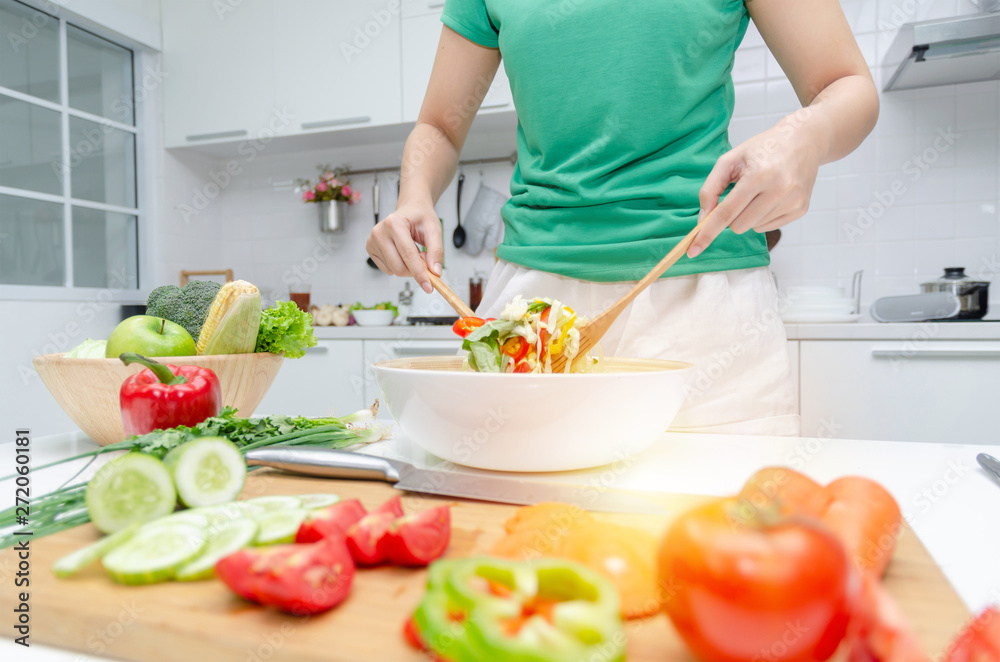 Diet. young pretty woman in green shirt standing and preparing the vegetables salad in bowl for good healthy in modern kitchen at home, healthy lifestyle, cooking, healthy food and dieting concept