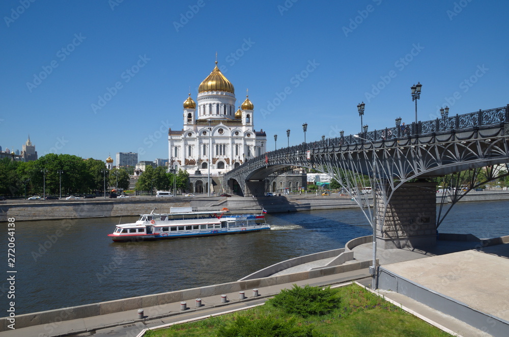 The Cathedral of Christ the Savior and the Patriarchal bridge. Pleasure boat floats on the Moscow river on a Sunny summer day. Moscow, Russia The Cathedral of Christ the Savior and the Patriarchal bridge. Pleasure boat floats on the Moscow river on a Sunny summer day. Moscow, Russia