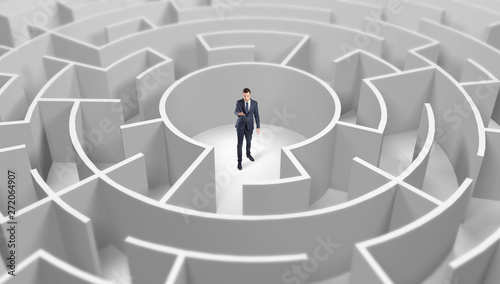 Young businessman standing in a middle of a 3d round maze 
