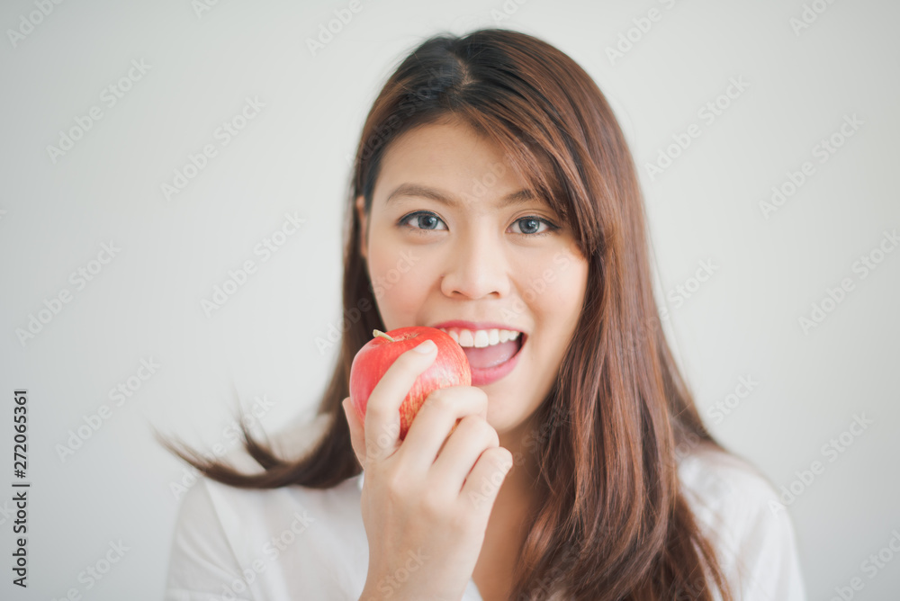 Closed up, Young Asian woman with long hair are smiling and biting red apple in white background. Closed up, Young Asian woman with long hair are smiling and biting red apple in white background.