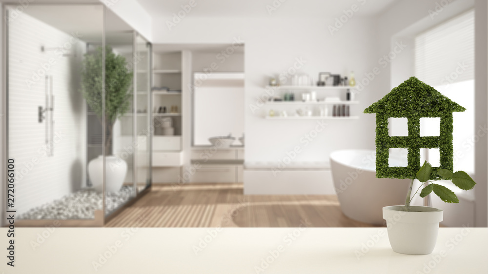 Fototapeta premium White table top or shelf with green plant in pot shaped like house, modern blurred bathroom with bathtub in the background, interior design, real estate, eco architecture concept idea