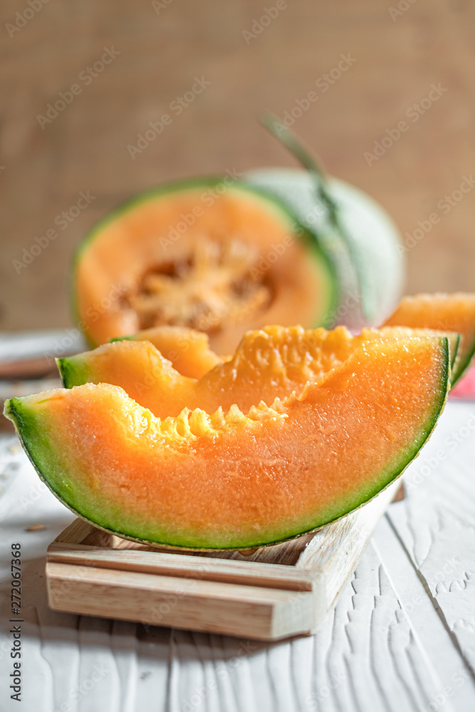 Fresh of whole and sliced orange melon or cantaloupe on tray board and background wooden table. Favorite fruit in summer concept.