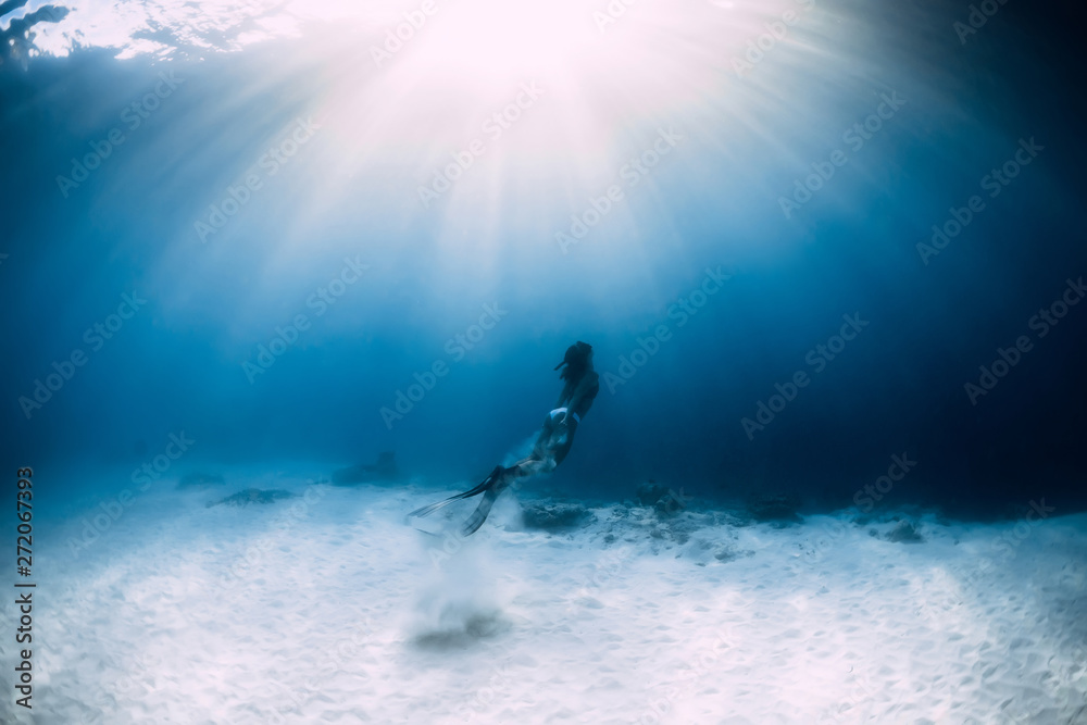 Woman freediver in bikini over sandy sea with fins. Freediving underwater in blue ocean