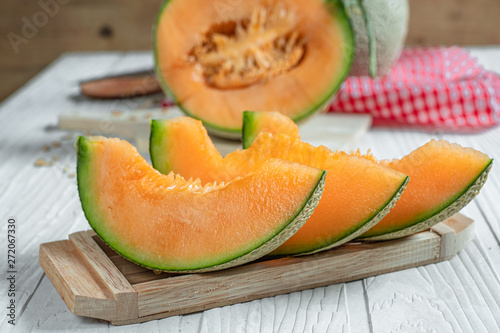 Fresh of whole and sliced orange melon or cantaloupe on tray board and background wooden table. Favorite fruit in summer concept. photo