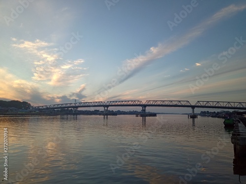 the sky when the sun will rise in the river with the bridge