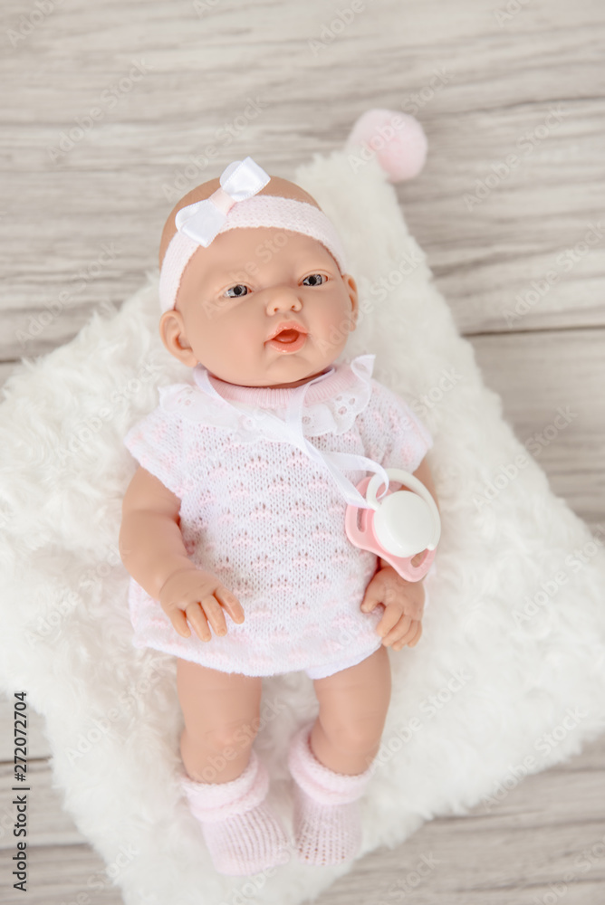 Cute Baby Doll in white pale clothes isolated on beige background. Cute Baby Doll in white pale clothes isolated on beige background.