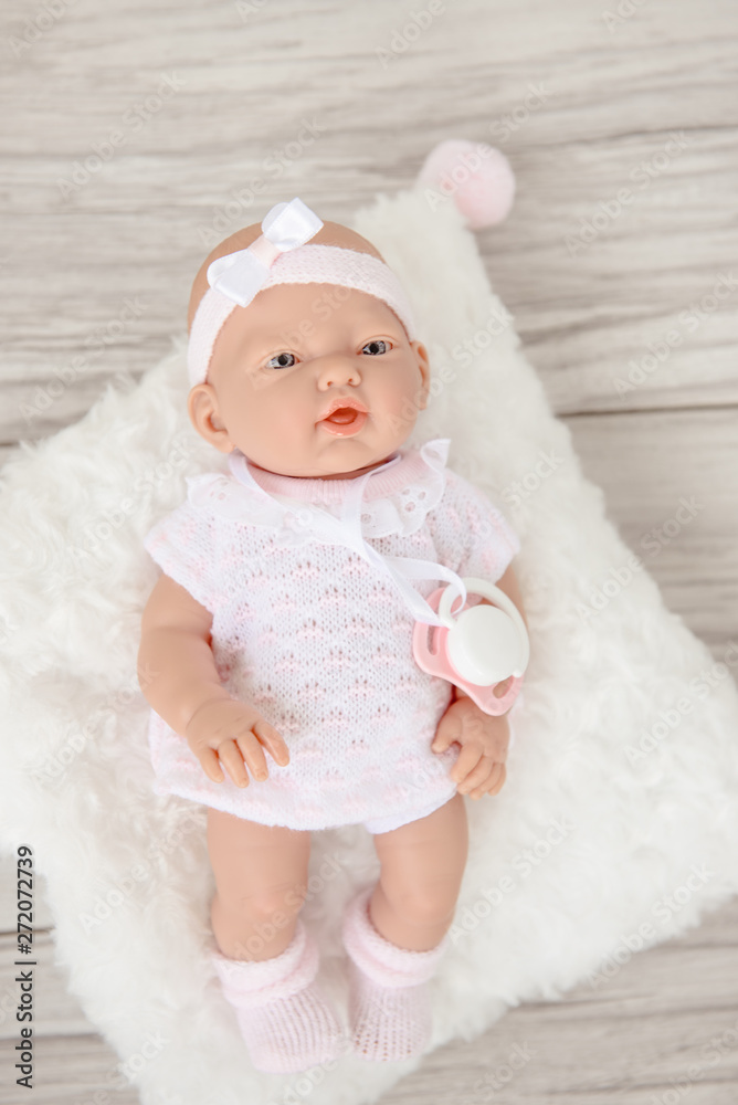 Cute Baby Doll in white pale clothes isolated on beige background. Cute Baby Doll in white pale clothes isolated on beige background.