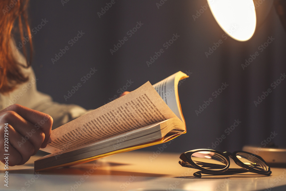 Woman reading book at evening at home close up - obrazy, fototapety, plakaty 