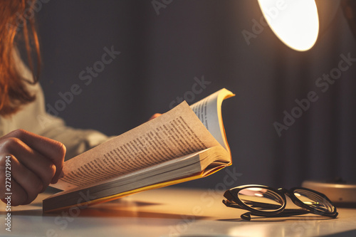 Woman reading book at evening at home close up photo