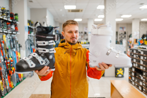 Man shows ski or snowboarding boots in sports shop photo