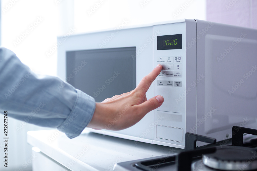 Woman warms up food in the microwave for lunch in the kitchen at home Woman warms up food in the microwave for lunch in the kitchen at home