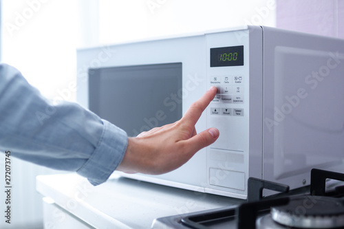 Woman warms up food in the microwave for lunch in the kitchen at home