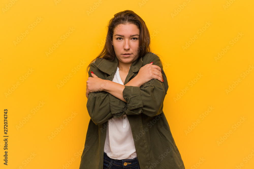 Young european woman isolated over yellow background going cold due to low temperature or a sickness. Young european woman isolated over yellow background going cold due to low temperature or a sickness.