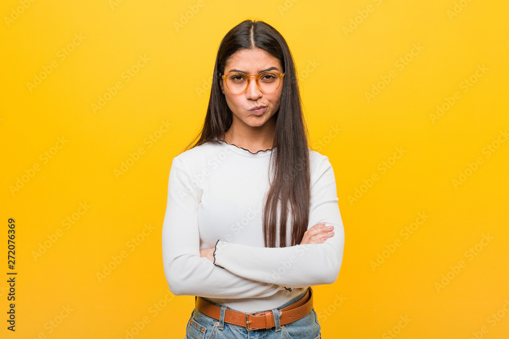 Young pretty arab woman against a yellow background frowning face in displeasure, keeps arms folded. Young pretty arab woman against a yellow background frowning face in displeasure, keeps arms folded.