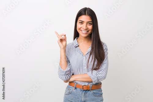 Young pretty arab woman smiling cheerfully pointing with forefinger away.