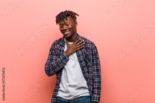Young african black man laughs out loudly keeping hand on chest.