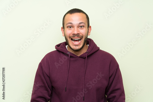 Colombian man with sweatshirt over green wall with surprise facial expression © luismolinero
