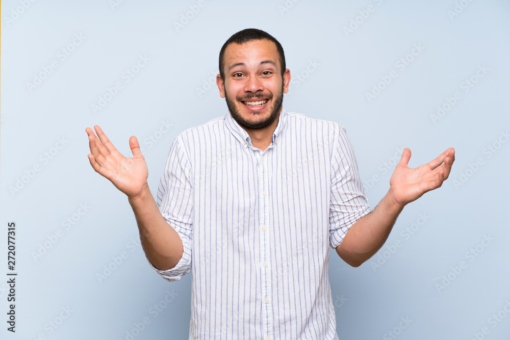 Naklejka premium Colombian man over isolated blue wall smiling a lot