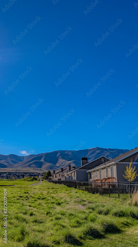 Panorama frame Houses on a lush grassy field under the blazing sun and vivid blue sky