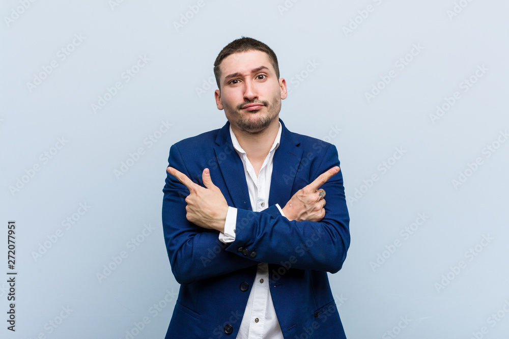Young business caucasian man points sideways, is trying to choose between two options. Young business caucasian man points sideways, is trying to choose between two options.