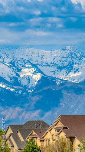 Panorama Houses and lush green trees with snow capped mountain in the background © Jason