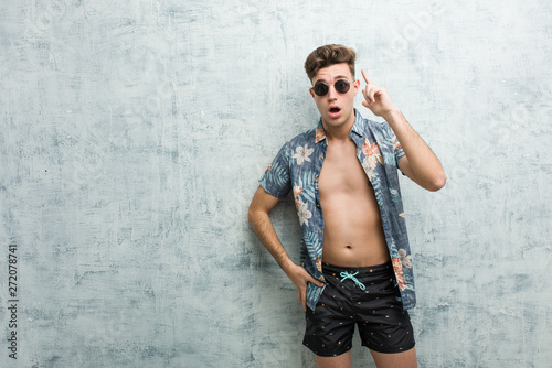 Young caucasian man wearing a swimsuit having an idea, inspiration concept.