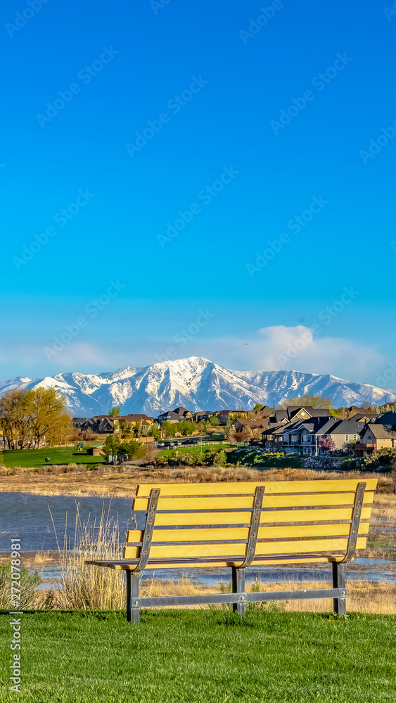 Panorama frame Bench on a grassy field overlooking lake and snowy mountain against blue sky