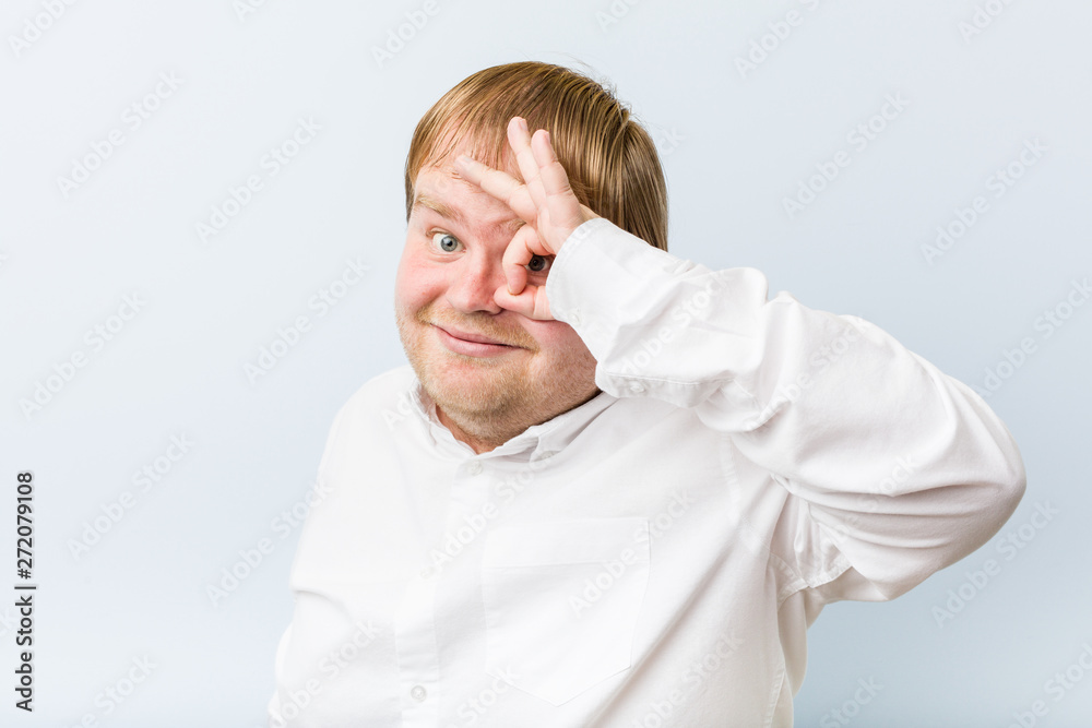 Young authentic redhead fat man excited keeping ok gesture on eye. Young authentic redhead fat man excited keeping ok gesture on eye.