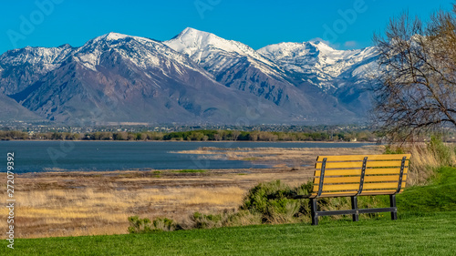 Panorama Bench on the lush field with a view of a lake and towering snow capped mountain