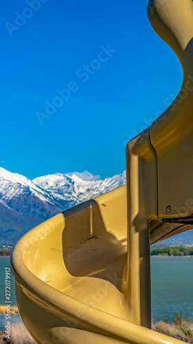 Panorama frame Close up of a spiral slide at a sunny playground with view of a lake