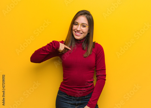Young intellectual woman person pointing by hand to a shirt copy space, proud and confident
