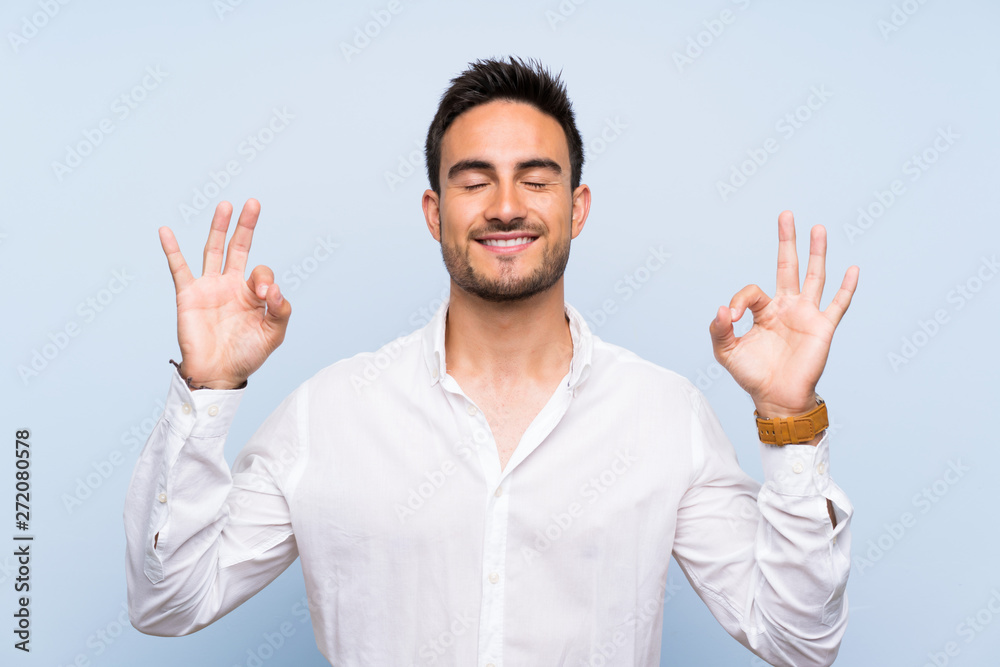 Handsome young man over isolated blue background in zen pose Handsome young man over isolated blue background in zen pose
