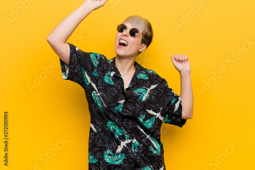 Young curvy woman wearing a summer look celebrating a special day, jumps and raise arms with energy.