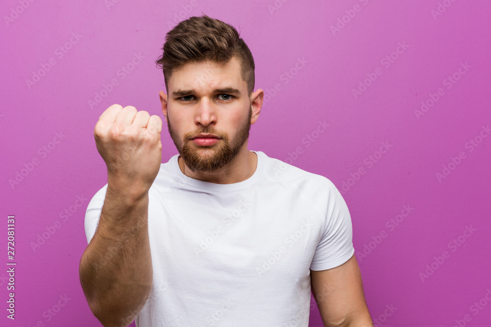 Fototapeta premium Young handsome caucasian man showing fist to camera, aggressive facial expression.