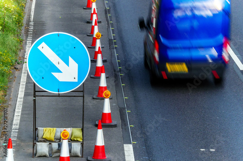 UK Road Services Roadworks Cones and directional Signs on motorway with blue van passing