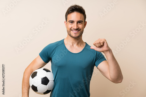 Handsome sport man over isolated background holding a soccer ball
