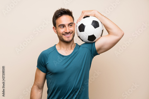Handsome sport man over isolated background holding a soccer ball