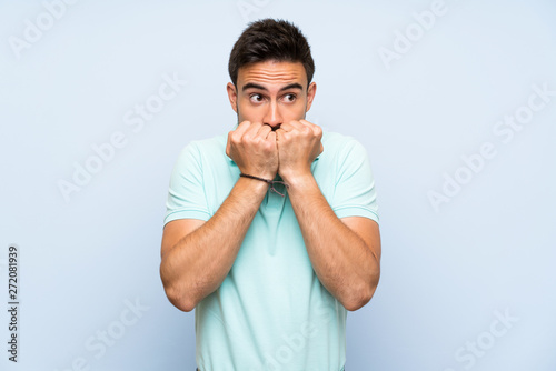 Handsome young man over isolated background nervous and scared putting hands to mouth