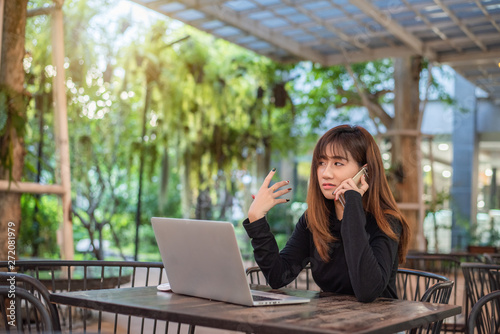 Happy young hipster woman talking on the phone and using tablet computer in at cafe.