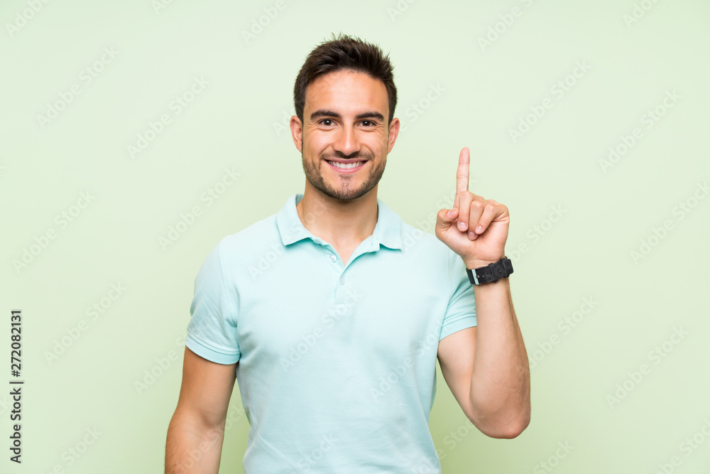Handsome young man over isolated background showing and lifting a finger in sign of the best Handsome young man over isolated background showing and lifting a finger in sign of the best