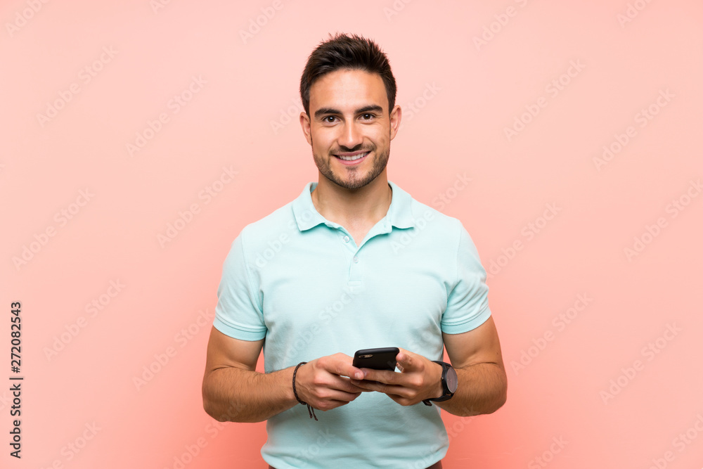 Handsome young man over isolated background sending a message with the mobile